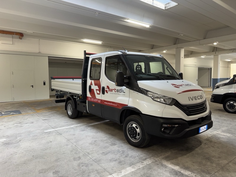 Autocarro Iveco bianco con cassone aperto, logo aziendale sulle portiere e grafica rossa lungo la cabina.