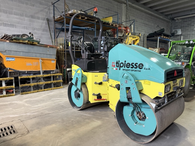 Rullo compattatore turchese e giallo con logo Tipiesse applicato sul cofano, fotografato in officina.